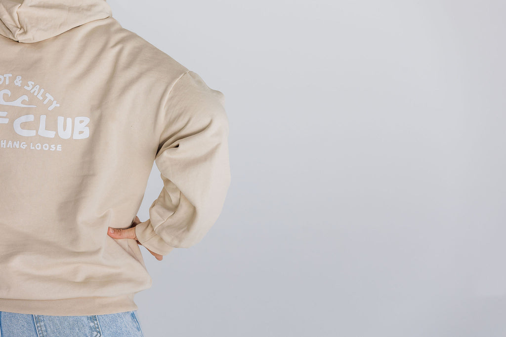 Beige hoodie with text on the back against a light gray background